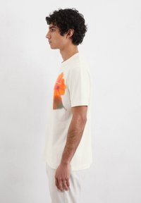 Cream short-sleeve t-shirt featuring a vibrant orange floral print on the front, crafted from soft fabric with a relaxed fit.