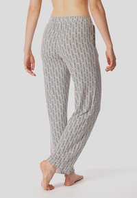 Los pantalones de lounge con estampado presentan un diseño geométrico multicolor, cinturilla elástica y bolsillos laterales. Están confeccionados con una tela suave y ligera.