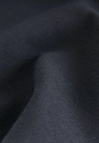 Tumedat meresised kangad, millel on sile, kergelt tekstureeritud pind, mis näitab värvi ja valguse peegeldumise peeneid varieeringuid.