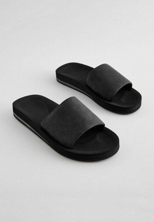 Čierne šľapky so štruktúrovaným horným remienkom, otvorenou špičkou a drážkovou podošvou. Doplnkové jemné perforované vzory na remienku.