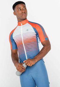 Jersey de ciclismo de manga corta en degradado rojo y azul con rayas horizontales, cuenta con una cremallera frontal y un diseño ajustado, combinado con pantalones cortos azules.
