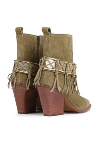 Botine din suede de măslin, cu toc din lemn, curele decorative împletite, accente metalice și ciucuri franjurați în jurul gleznei.