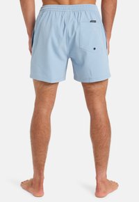 Light blue, short swim trunks made of textured fabric. Features an elastic waistband and a back pocket with a round black button.