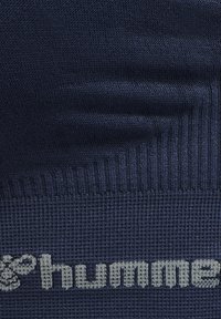 Granatowa skarpetka z teksturowanego materiału. Posiada prążkowany ściągacz i jasnoszare logo "hummel" w pobliżu dołu. Gładkie wykończenie na całej długości.