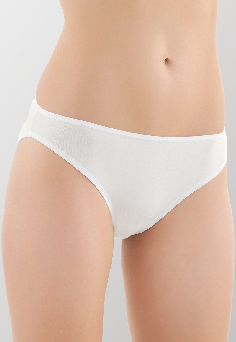 Slip in cotone bianco con una consistenza liscia e una cintura elastica stretta, caratterizzati da una copertura minima e un taglio a vita bassa.