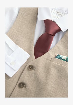 Beige vest met twee bruine knopen, wit shirt met knoopmanchetten, en een bordeauxrode stropdas. Pochet met groen en blauw bloemmotief.