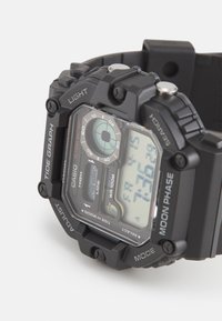 Montre numérique avec un boîtier et un bracelet en résine noire, dotée de plusieurs cadrans, boutons et d'un écran clair. Comprend des indicateurs de marée et de phase lunaire.