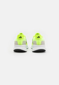 Baskets de sport jaune fluo avec des accents gris, un talon texturé et une semelle externe blanche. Présentant un logo noir à l'arrière et sur les côtés.