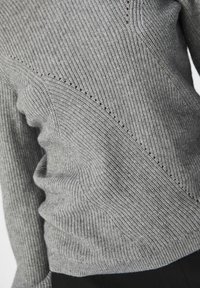 Gray ribbed sweater featuring diagonal knit patterns and subtle hole details, with a soft texture and fitted design.