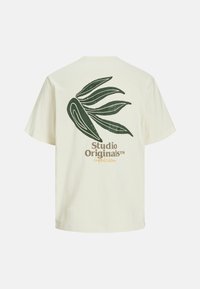 Kratka majica s kratkimi rokavi v kremni barvi, ki ima na hrbtu temno zeleno grafiko lista in spodaj zlat napis "Studio Originals".