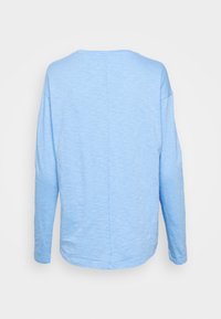 Světle modrý dlouhý rukáv top s volnějším střihem, kulatým výstřihem a texturovanou, mírně nepravidelnou tkaninou.