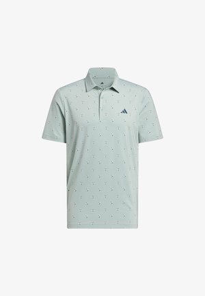 Polo de manga corta color verde claro con pequeños patrones oscuros en forma de cruz y un logotipo triangular azul marino en el pecho izquierdo.