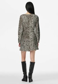 Blizganti sidabrinė ilgomis rankovėmis suknelė, aptempto silueto, su plėšytu apačios kraštu ir žėrinčiais blizgučiais. Derinama su juodais kelių aukščio platformos aulinukais.