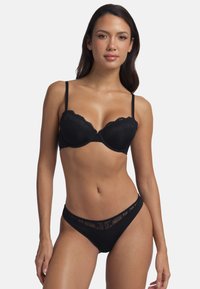 Soutien-gorge noir avec des bordures en dentelle, bonnets moulés, bretelles réglables, et un string assorti comportant une taille en dentelle transparente et une base en tissu uni.