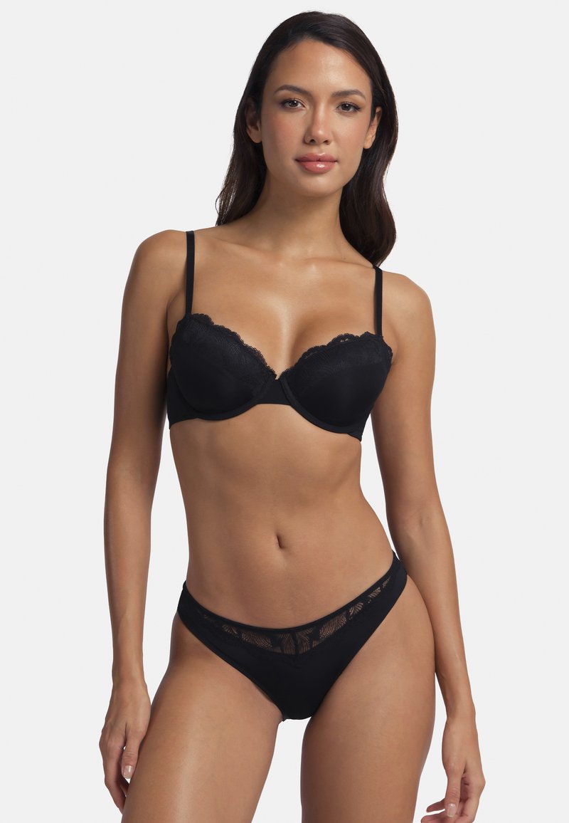 Soutien-gorge noir avec des bordures en dentelle, bonnets moulés, bretelles réglables, et un string assorti comportant une taille en dentelle transparente et une base en tissu uni.