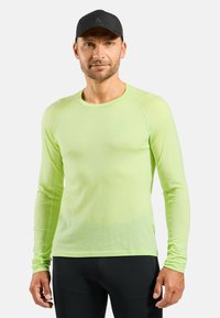 Long-sleeve, light green athletic shirt made of breathable fabric, featuring a rounded neckline and logo on the chest.