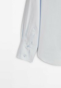 Poignet de chemise à manches longues bleu clair avec deux boutons et une fente de manche, présenté sur fond blanc.