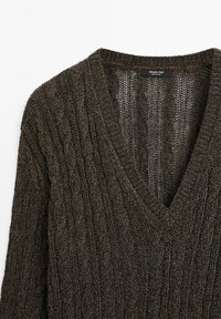 Pull marron foncé en maille torsadée avec col en V, manches longues et col côtelé, montrant la texture et les détails tissés.
