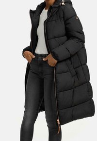 Lång svart puffjacka med huva, med quiltad textur, sidofickor och dragkedjestängning med rosaguldiga detaljer.