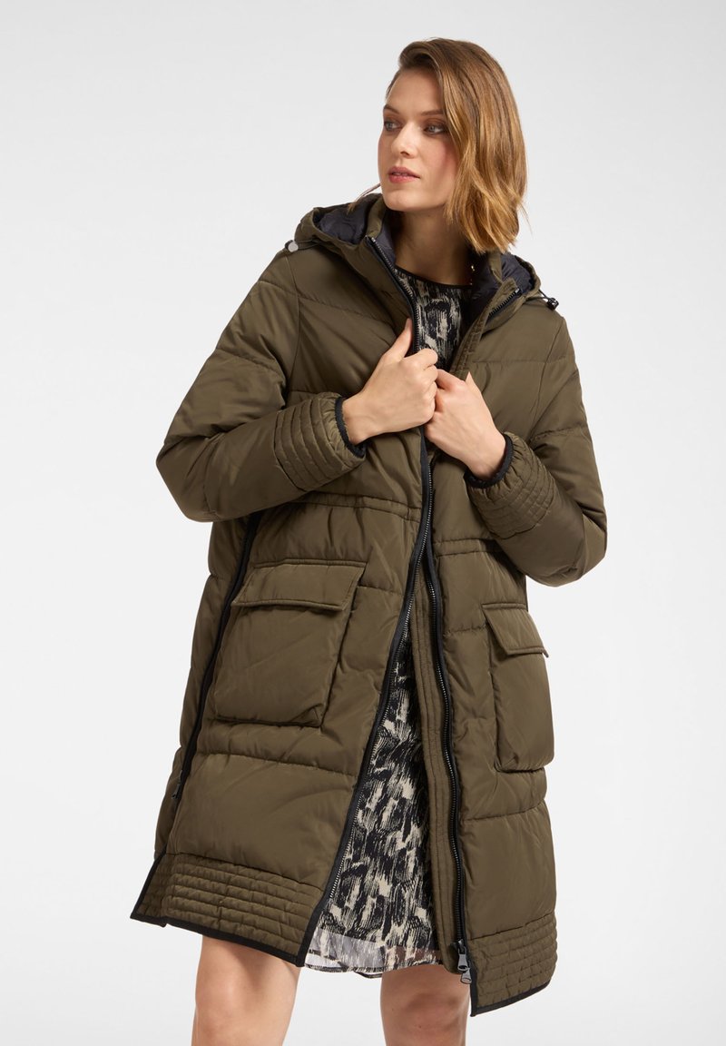 Ocieplany zielony oliwkowy płaszcz z zamkiem z przodu, kapturem i dużymi zewnętrznymi kieszeniami. Charakteryzuje si�ę teksturowanym przeszyciem wzdłuż dołu i mankietów.