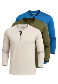 Tre långärmade Henley-tröjor i beige, olivgrön och blå, med rund hals och knappslå, visade lager på en vit bakgrund.