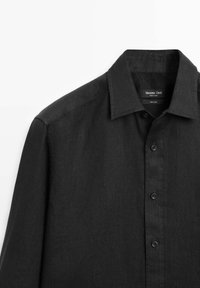 Camicia nera a maniche lunghe in lino con colletto e bottoni, vista della parte superiore anteriore e della spalla sinistra.