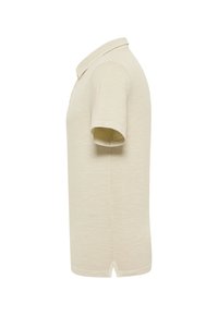 Polo beige à manches courtes vu de côté avec un col et une petite fente latérale à l'ourlet.