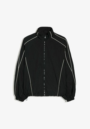Veste légère noire avec fermeture éclair frontale, poignets élastiques et passepoils blancs le long des manches et des épaules.