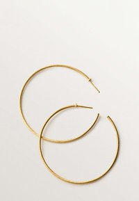 Pendientes de aro dorados con un acabado texturizado, que presentan una forma circular delgada y un cierre de tornillo seguro. Un pendiente es ligeramente más grande que el otro.