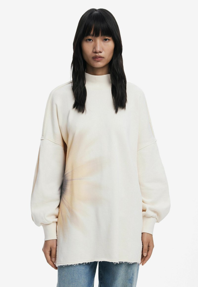 Sweatshirt oversize beige chiaro con maniche lunghe a palloncino, colletto alto e motivo tie-dye texturizzato nella parte inferiore anteriore. Orlo sfrangiato.