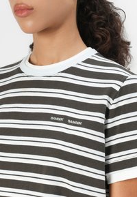 Brun og hvid stribet t-shirt med rund halsudskæring, der har en glat tekstur og et broderet logo på brystet.