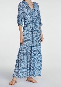 Sininen kuvioitu maksi mekko, jossa on V-pääntie, kolmannen osa hihat, joustava vyötärö ja kerroksellinen helma. Kevyt kangas, jolla on valuva rakenne.