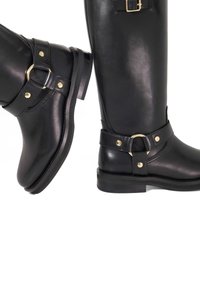 Black leather knee-high boots with a glossy finish, featuring gold hardware accents and adjustable straps at the ankle and calf areas.