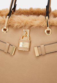 Borsa a tracolla beige con texture, rifiniture morbide, chiusura e accessori in tono oro, e due manici neri e beige.