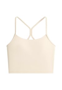 Top court beige avec fines bretelles tressées qui se croisent dans le dos, design simple, tissu lisse, sans motifs.