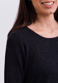 Ciemnoszary sweter dzianinowy o miękkiej fakturze, okrągłym dekolcie i długich rękawach, charakteryzujący się luźnym krojem i minimalną ilością szwów.
