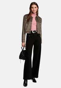 Veste cropped en suède grise avec poches avant, col roulé en maille rose, pantalon noir à taille haute et coupe large, et sac à main noir avec œillets.