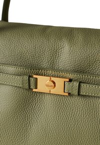 Grüne Lederhandtasche mit strukturiertem Finish, ausgestattet mit einem goldfarbenen Metallschluss und passender Stichdetailierung. Strukturierte Form mit Griffen.