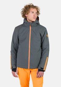 Grau Jacke mit einem orangen Frontreißverschluss, Seitentaschen und orangen Akzenten an den Ärmeln; verfügt über eine Kapuze und ein Logo-Patch auf der Schulter.