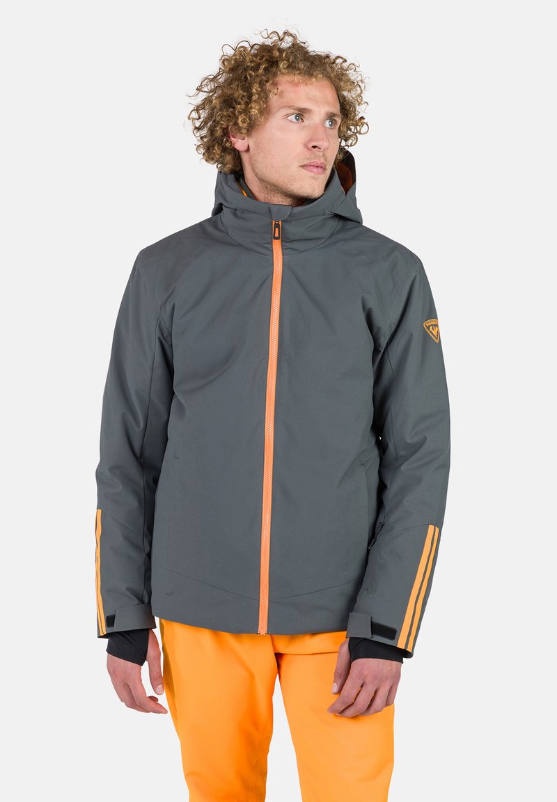 Grau Jacke mit einem orangen Frontreißverschluss, Seitentaschen und orangen Akzenten an den Ärmeln; verfügt über eine Kapuze und ein Logo-Patch auf der Schulter.
