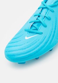 Türkiz színű foci cipő, texturált felsőrésszel, fehér Nike logóval és bonyolult mintázattal. Az összeillő türkiz színű fűzők.