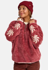 Pullover in pile color bordeaux con ricami crema svolazzanti sulle maniche, zip frontale a mezza lunghezza e tessuto morbido e strutturato.