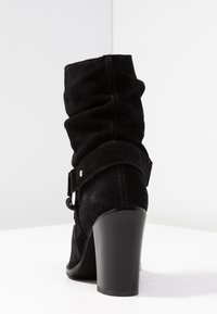 Mustat mokkapintaiset nilkkurit, joissa on rennon muotoinen design. Kengissä on leveä nauha hopeisilla yksityiskohdilla ja paksu korko. Yhteensä sileäpintainen rakenne.