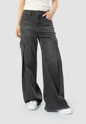 Black, wide-leg cargo pants with side pockets, made from denim material; features a button closure and a relaxed fit. Worn with white sneakers.