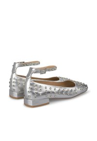 Ballerine argento con punta affusolata, decorate con borchie e cinturini alla caviglia, dotate di un tacco a blocco basso e una texture in pelle liscia.
