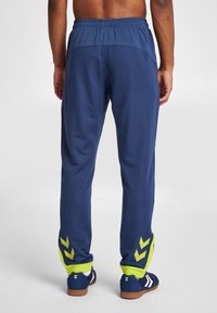 Marina atletiska byxor med en texturerad design, med gröna detaljer vid cuffarna och triangelmönster, elastisk midja och smal passform.