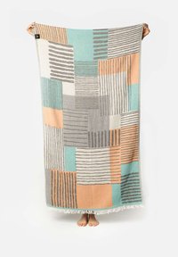 Coperta multicolore con un motivo geometrico che presenta sezioni in teal, pesca, grigio e beige, rifinita con bordi frangiati.
