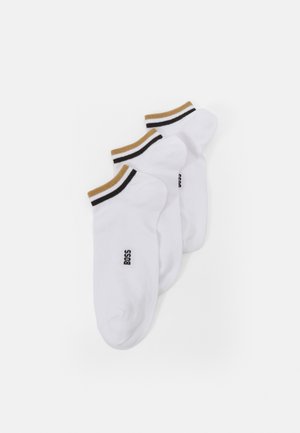Chaussettes blanches à la cheville avec des bords rayés marron et noir, arborant un petit logo "BOSS" noir sur le côté. Matériau doux, design décontracté.