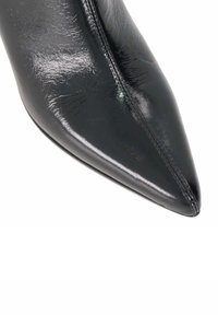 Black patent leather high-heeled shoe with a pointed toe, featuring a smooth surface, subtle stitching, and a sleek design.