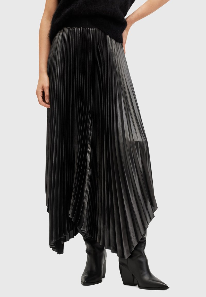Black pleated skirt made of glossy fabric, featuring a high waist and asymmetrical hem, paired with knee-high black boots.